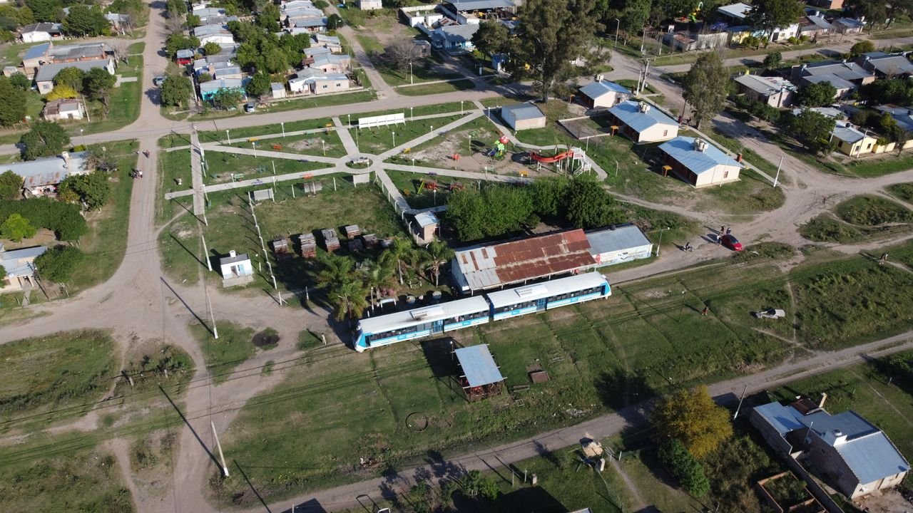 services-02 Aerial view of Cote-lai, Chaco, featuring a train and small town layout on a sunny day.