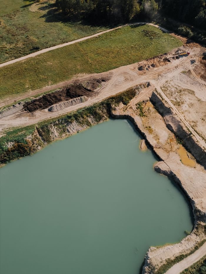 Drone shot of a mining site next to a green waterbody near Riga, Latvia.