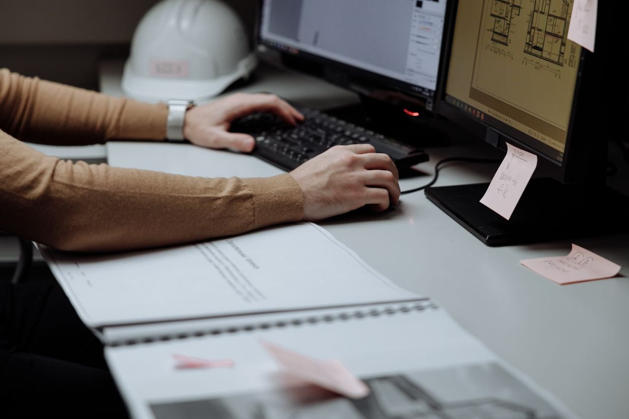 Architect focused on digital design at dual monitors in a modern workspace.